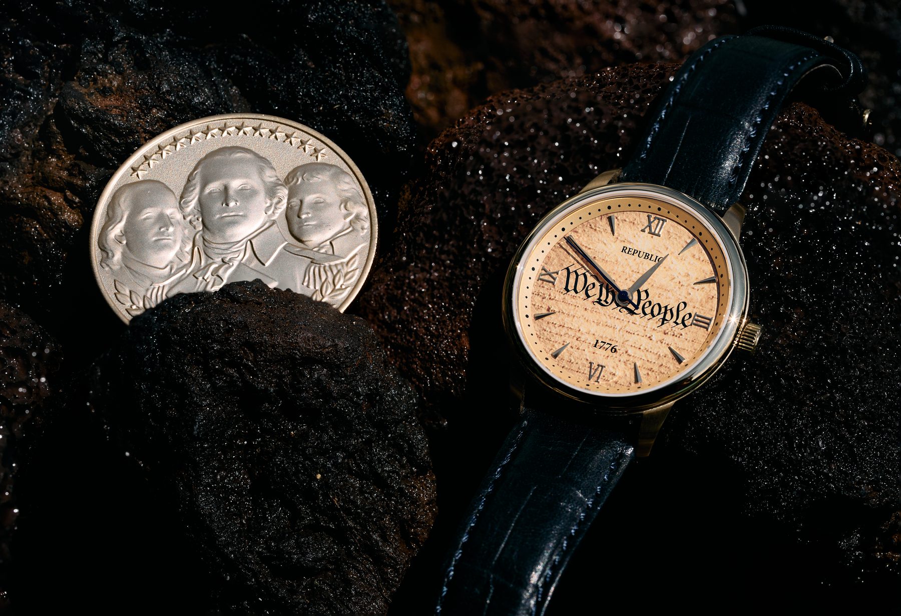 A Founders Republic timepiece beside its companion medallion on volcanic rock